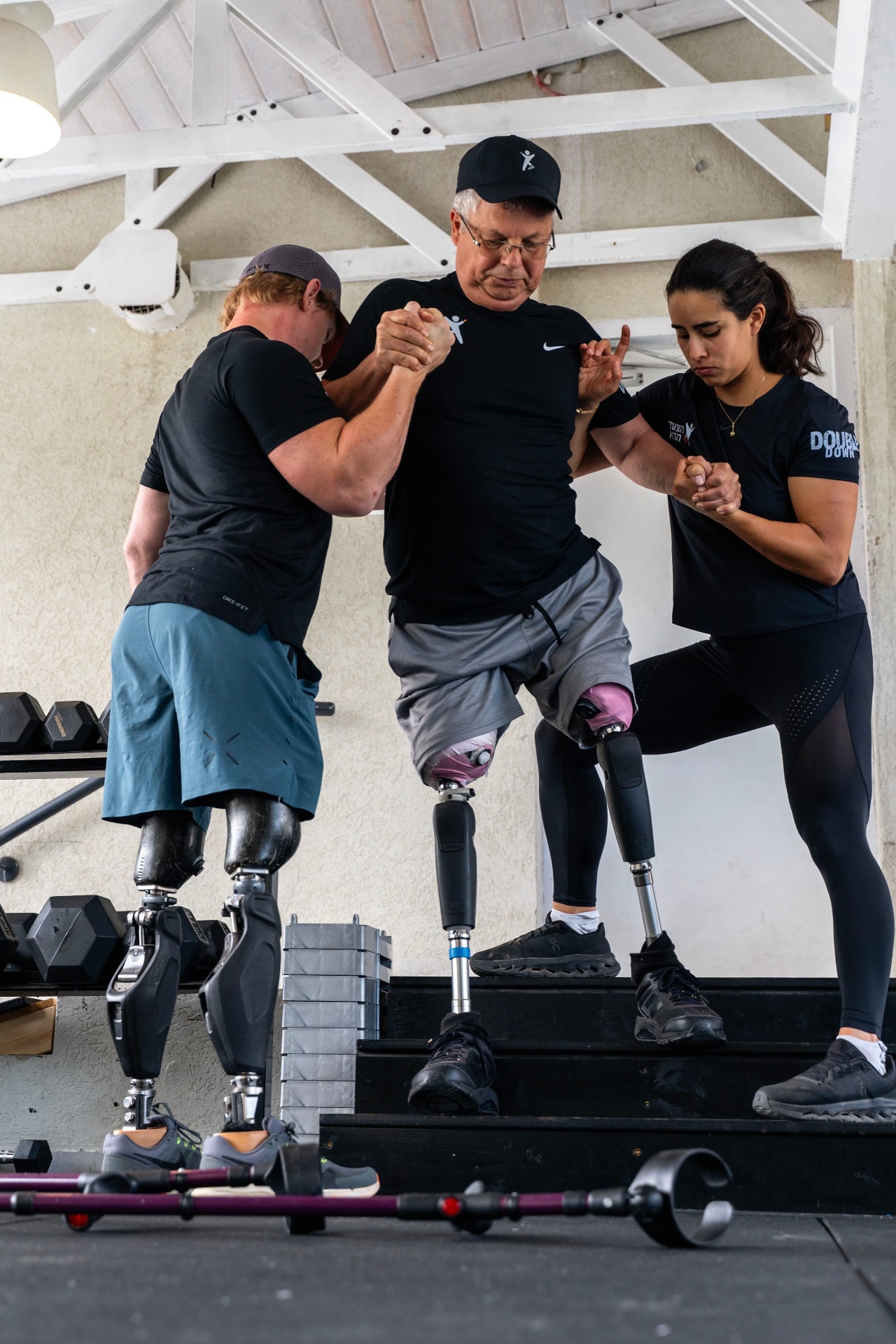 Double amputee stepping up with the support of two trainers