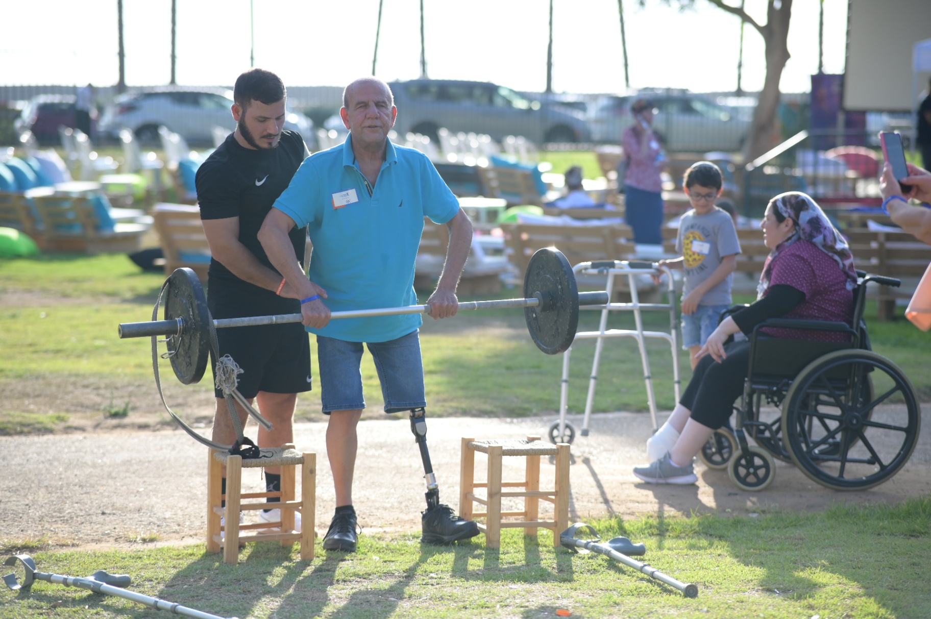 Amputee veteran lifting weights with a trainer at an outdoor event